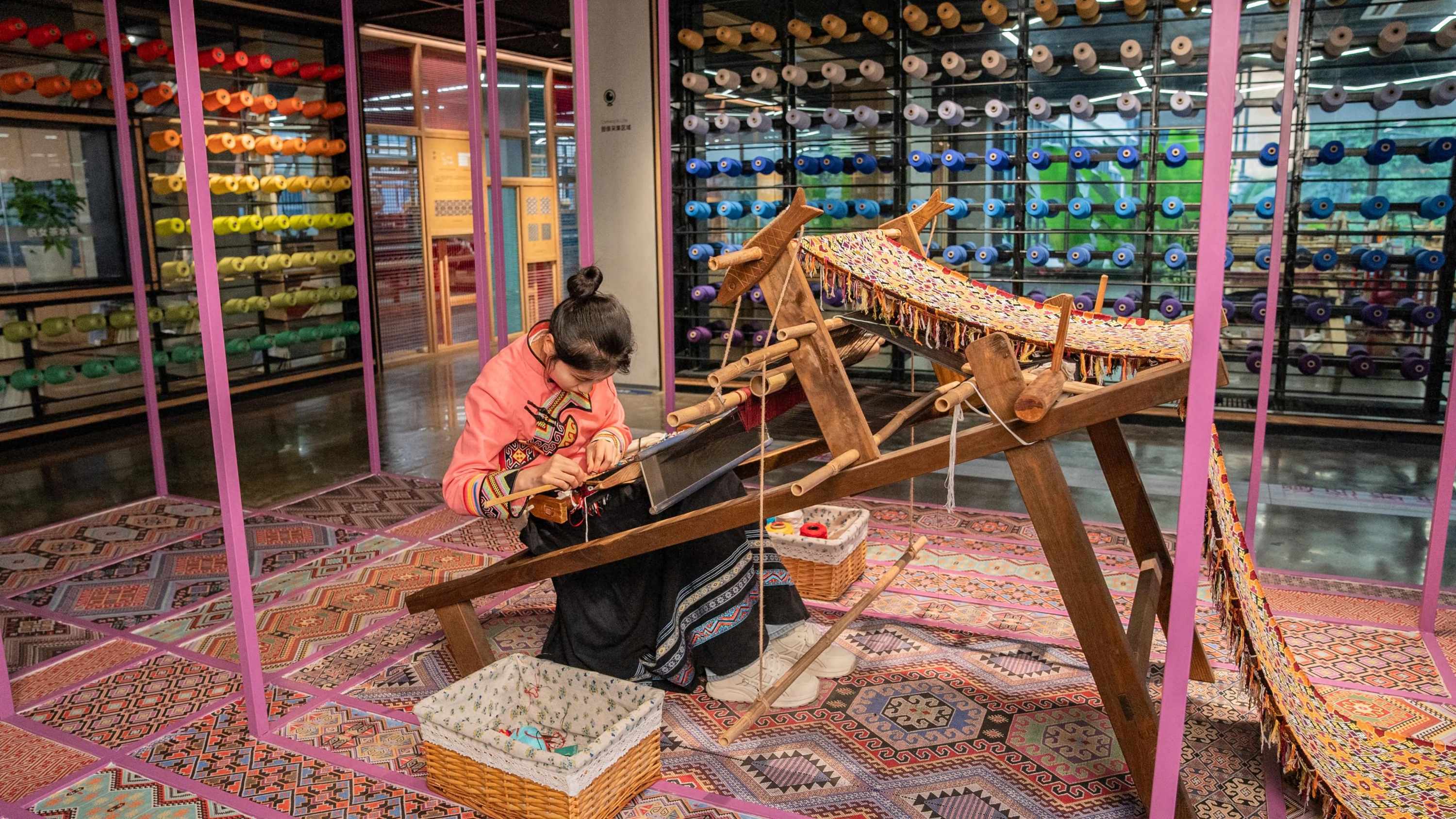 A weaver at a traditional loom in the Tujia Brocade Art Museum