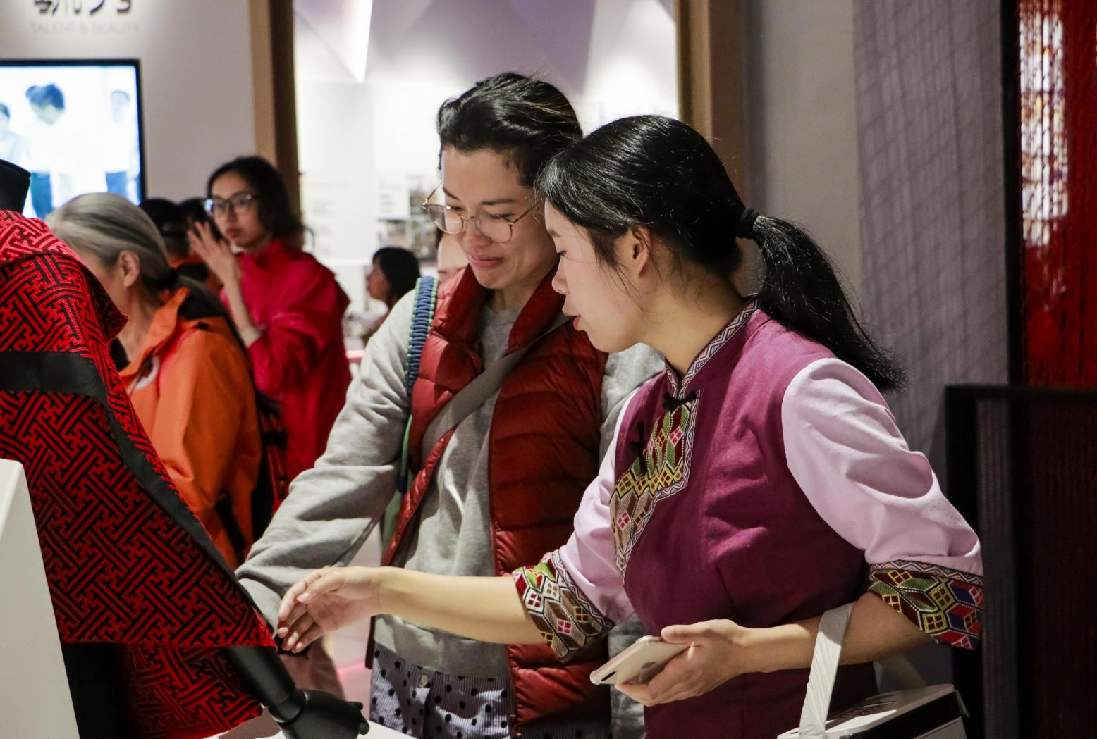 Visitors examining Tujia brocade with a museum guide